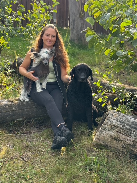 Gabriella sitter i gräset med sina två hundar